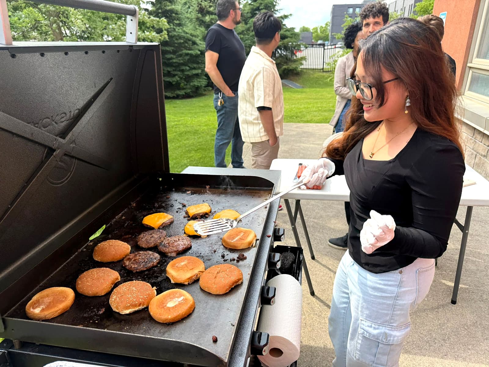Resident flipping burgers on the griddle at the 17Hundred Simcoe North BBQ day