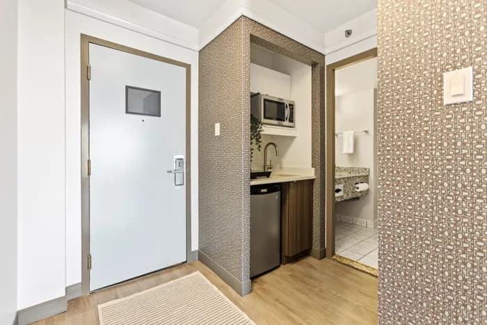 Chic apartment entryway featuring sleek cabinetry, modern sink, and convenient mini-fridge.