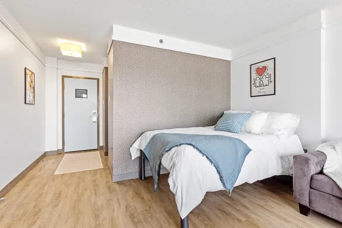 Chic bedroom with a cozy bed, modern decor, and stylish wooden flooring, perfect for relaxation.