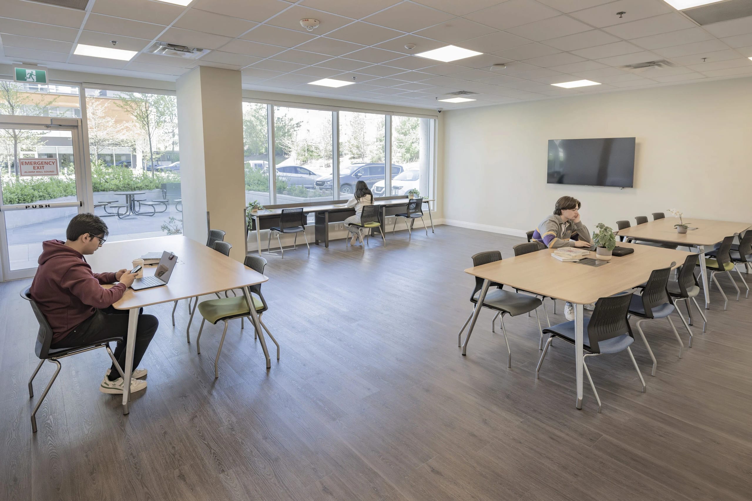 Students studying at tables in a bright shared lounge at a Canadian Student Living residence