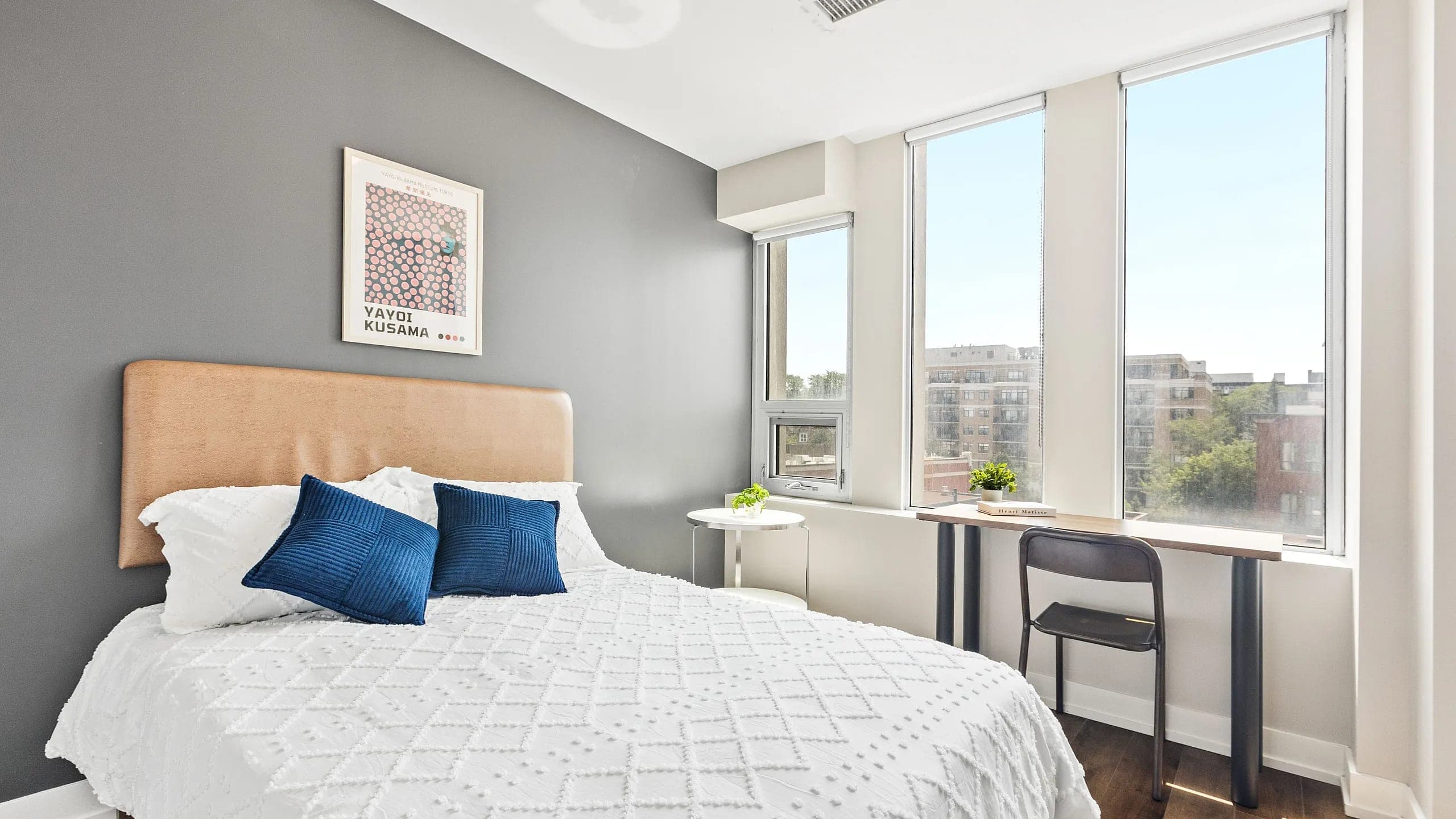 Bright and modern bedroom with blue pillows and city views.
